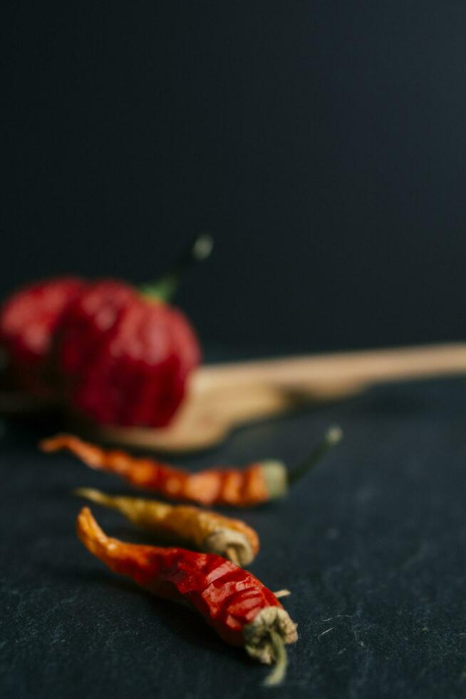 hetaste peppar i de värld. trinidad scorpion butch, tusentals av gånger Mer kryddad än havanna. på svart skiffer bakgrund, med naturlig ljus. kryddad mörk mat mat begrepp. foto