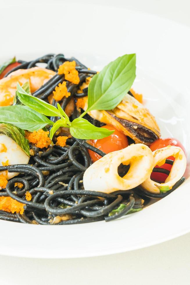 svart spagetti med skaldjur i vit platta foto