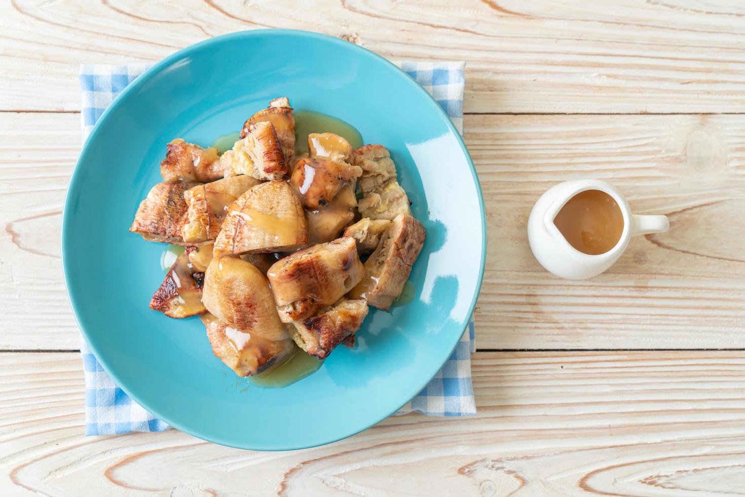 grillade bananer med kokosnötsamelsås på tallriken foto