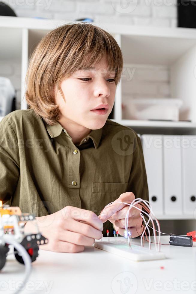 trevlig pojke som konstruerar en robotbil foto