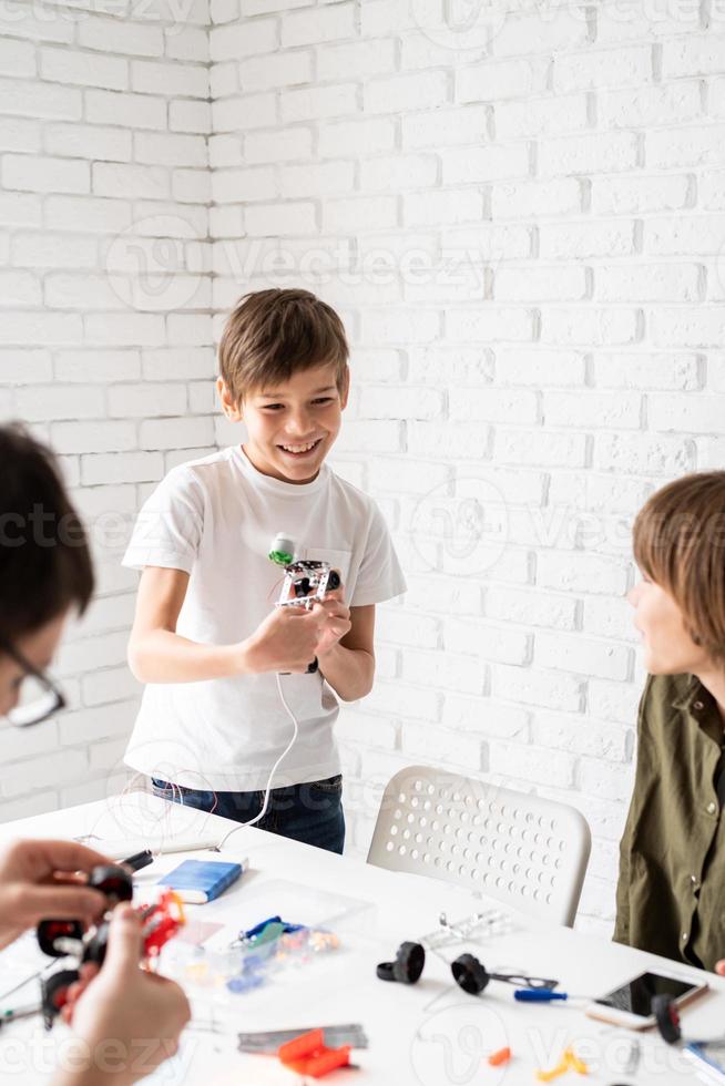 unga pojkar som har kul att konstruera robotbilar på verkstaden foto