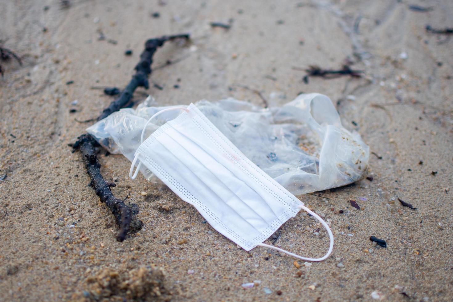 använd mask under covid 19 kastades på sandstranden. ämnet är begravd. foto