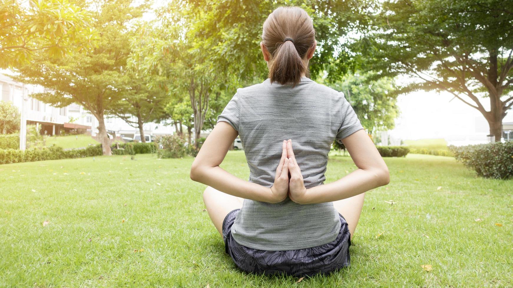 närbild av kvinna som gör yoga i grön trädgård foto