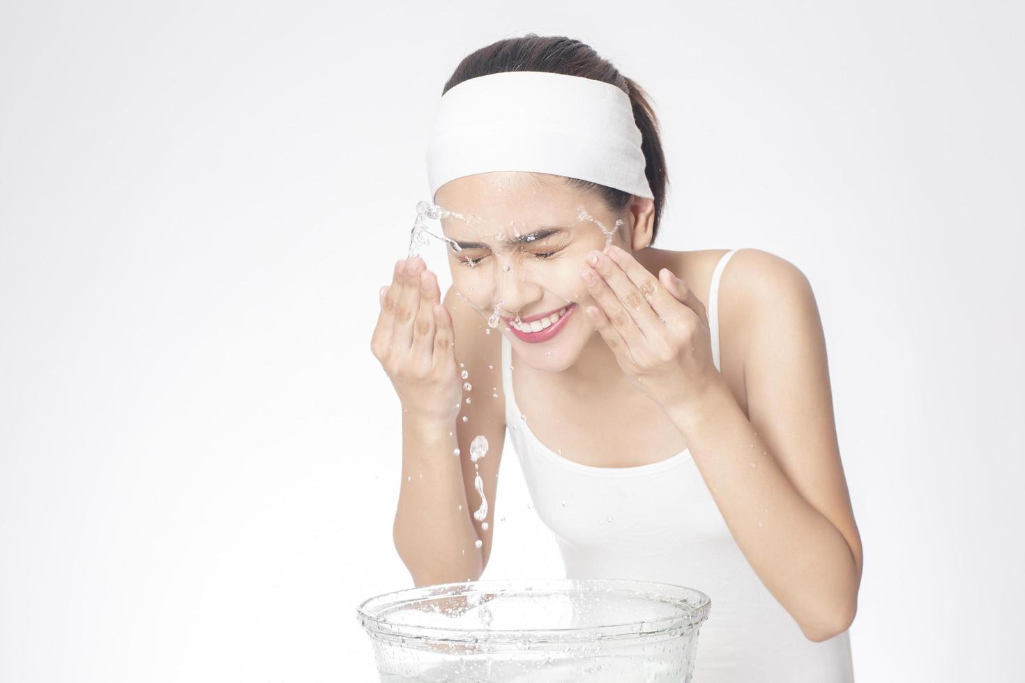vacker kvinna tvättar ansiktet på vit bakgrund foto