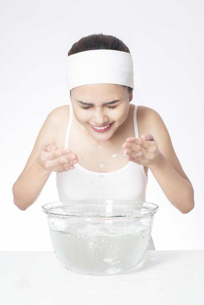 vacker kvinna tvättar ansiktet på vit bakgrund foto