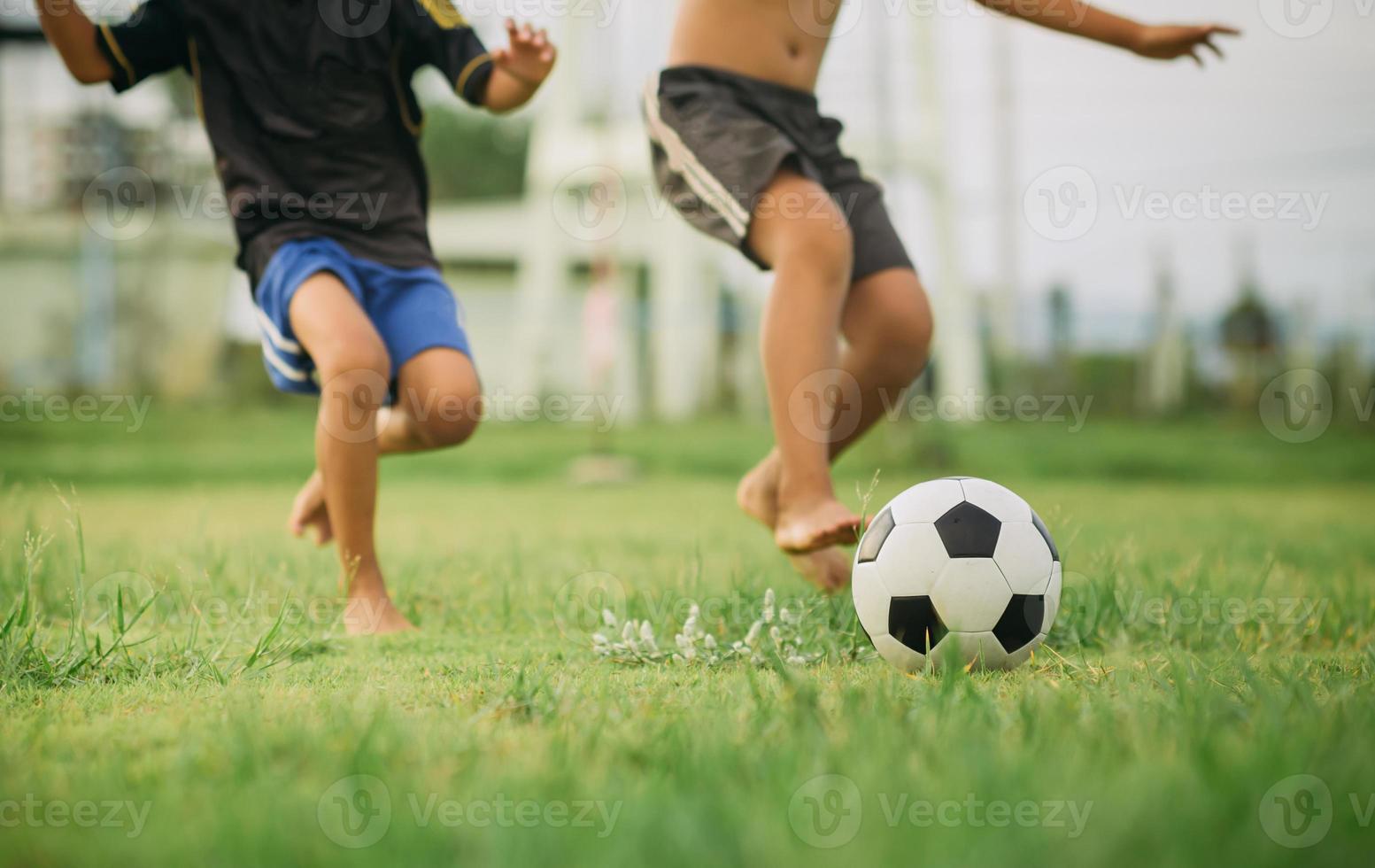 action sport utomhus av en grupp barn som har kul att spela fotboll fotboll för träning i gemenskapens lantliga område under skymningssolnedgången. foto