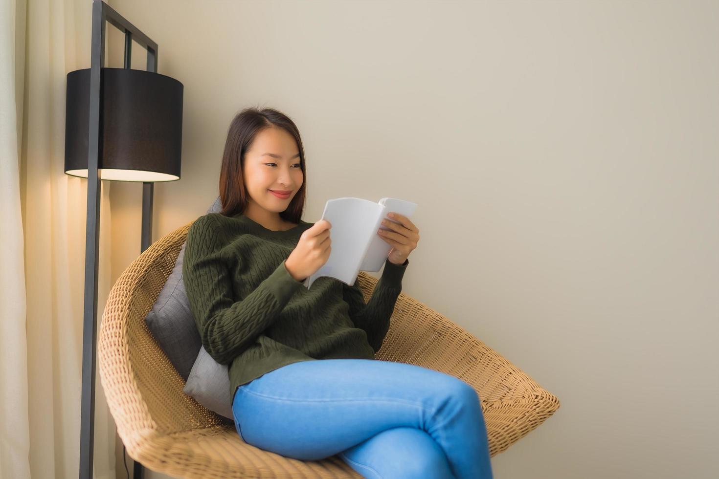 stående vackra unga asiatiska kvinnor som läser bok och sitter på soffstol foto