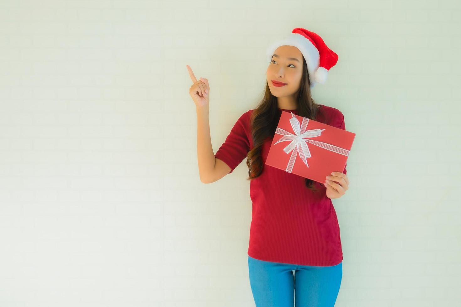 stående vackra unga asiatiska kvinnor bär santa hatt i julfestival med presentask foto