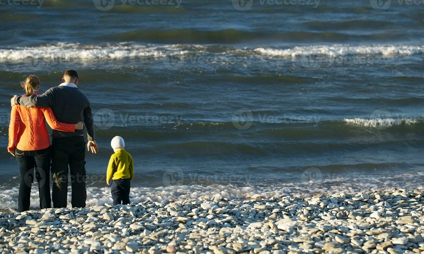 familj av tre på sten strand foto