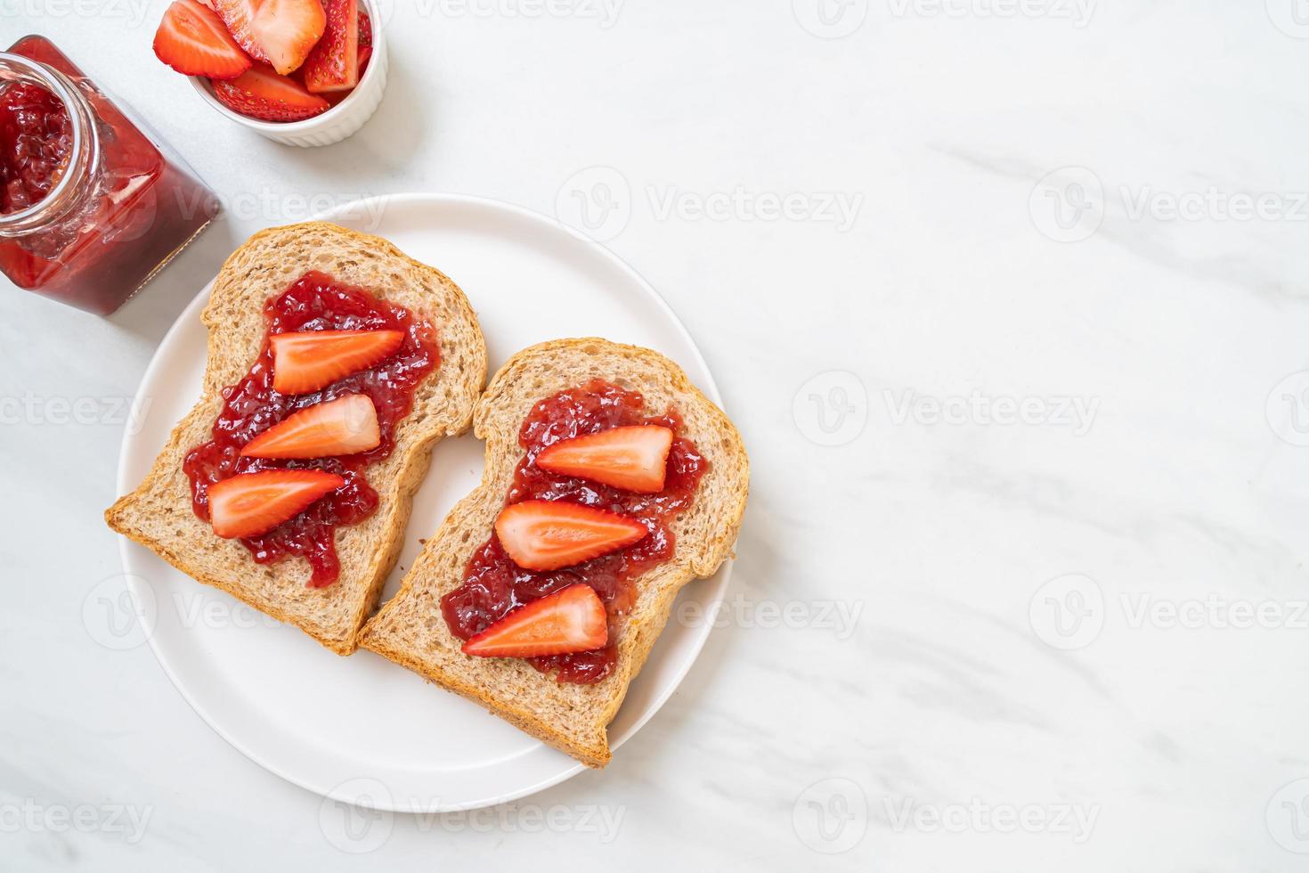 hemlagat fullkornsbröd med jordgubbssylt och färsk jordgubbe foto