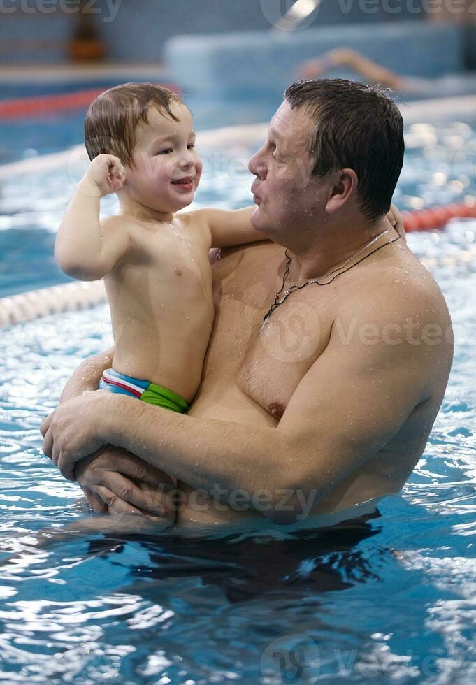 farfar som leker med sitt barnbarn i en pool foto