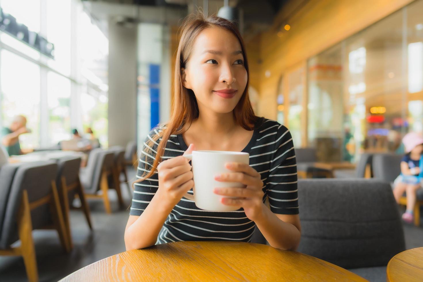 porträtt vackra unga asiatiska kvinnor i kafé och restaurang med mobiltelefon foto