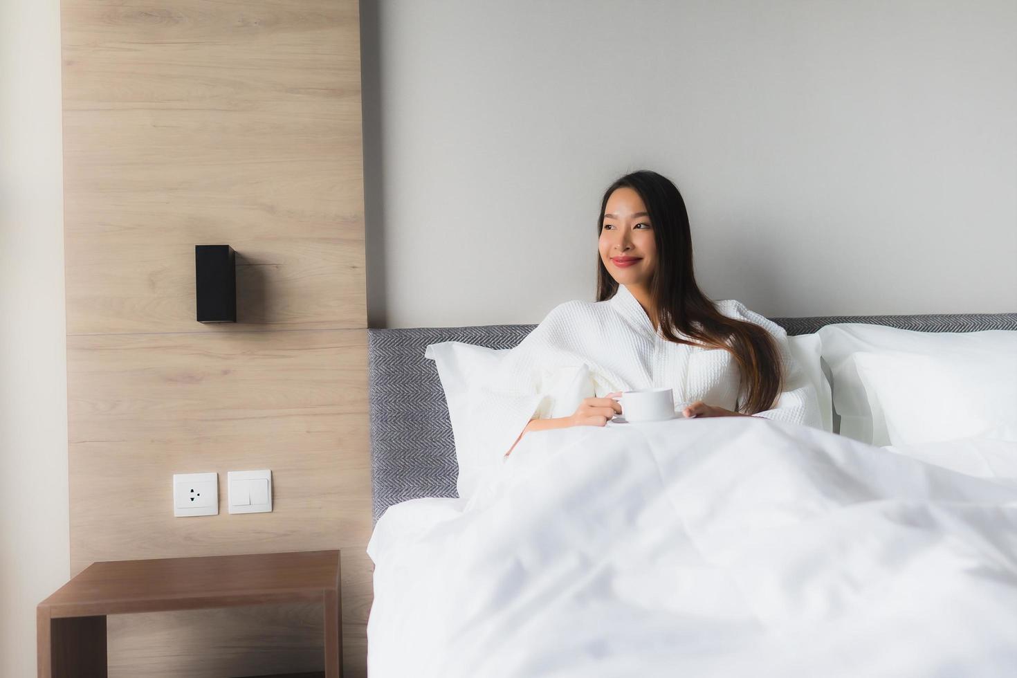 stående vackra unga asiatiska kvinnor med kaffekoppen på sängen foto