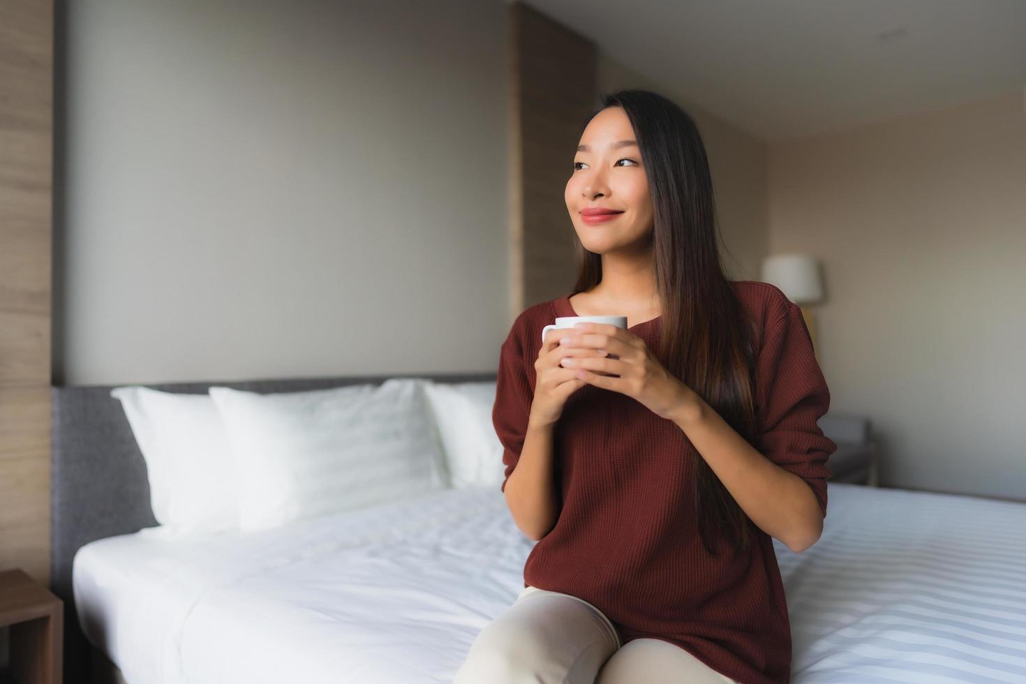 stående vackra unga asiatiska kvinnor med kaffekoppen på sängen foto