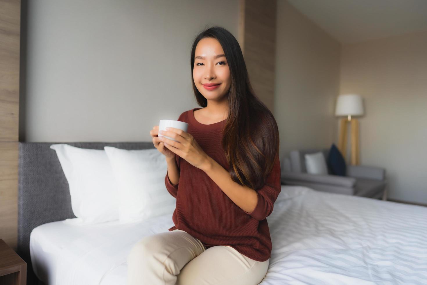 stående vackra unga asiatiska kvinnor med kaffekoppen på sängen foto