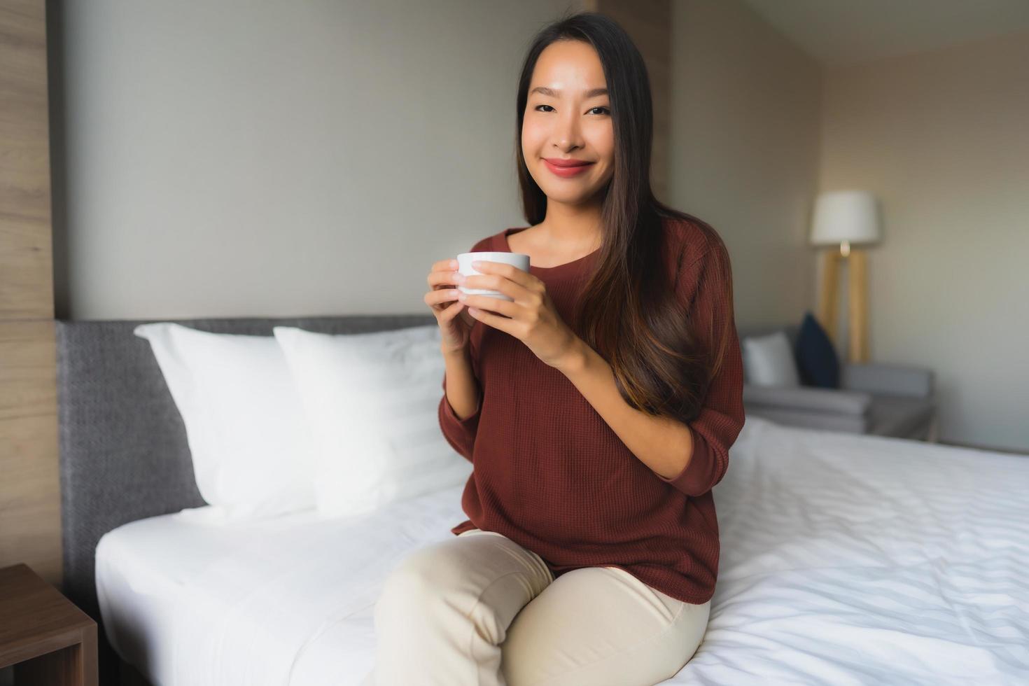 stående vackra unga asiatiska kvinnor med kaffekoppen på sängen foto