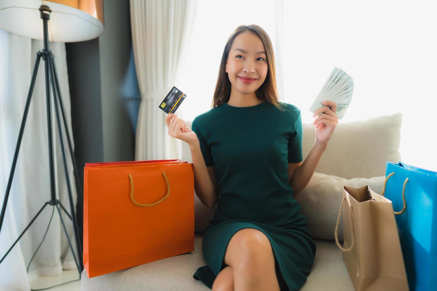 stående vackra unga asiatiska kvinnor som använder datorbärbar dator eller smart och mobiltelefon med kreditkort för online-shopping foto