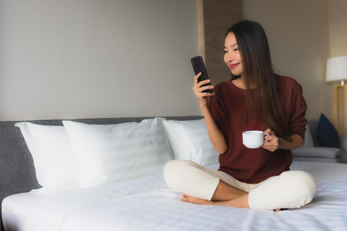 stående vackra unga asiatiska kvinnor lyckligt leende med kaffe och mobiltelefon foto
