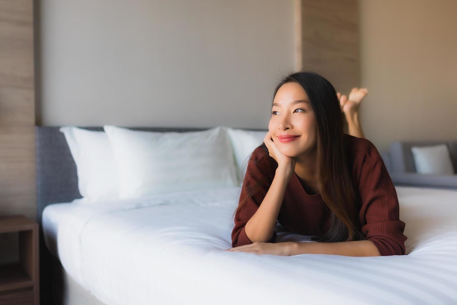 stående vackra unga asiatiska kvinnor lyckligt leende koppla av på sängen foto