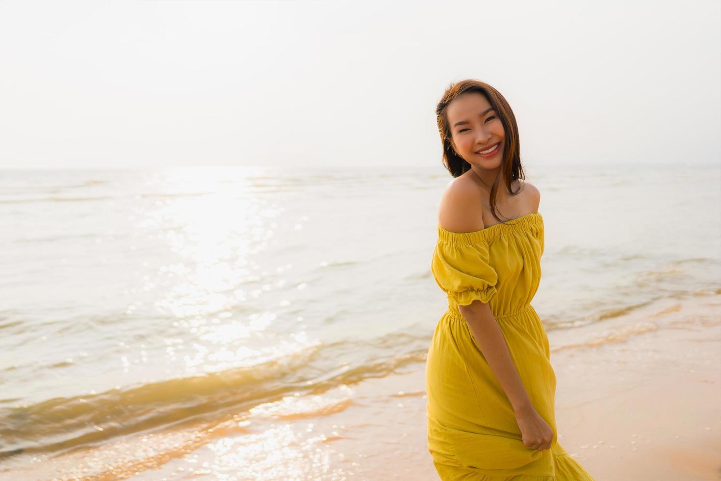 porträtt vacker ung asiatisk kvinna promenad på stranden och havet havet med leende glad koppla av foto
