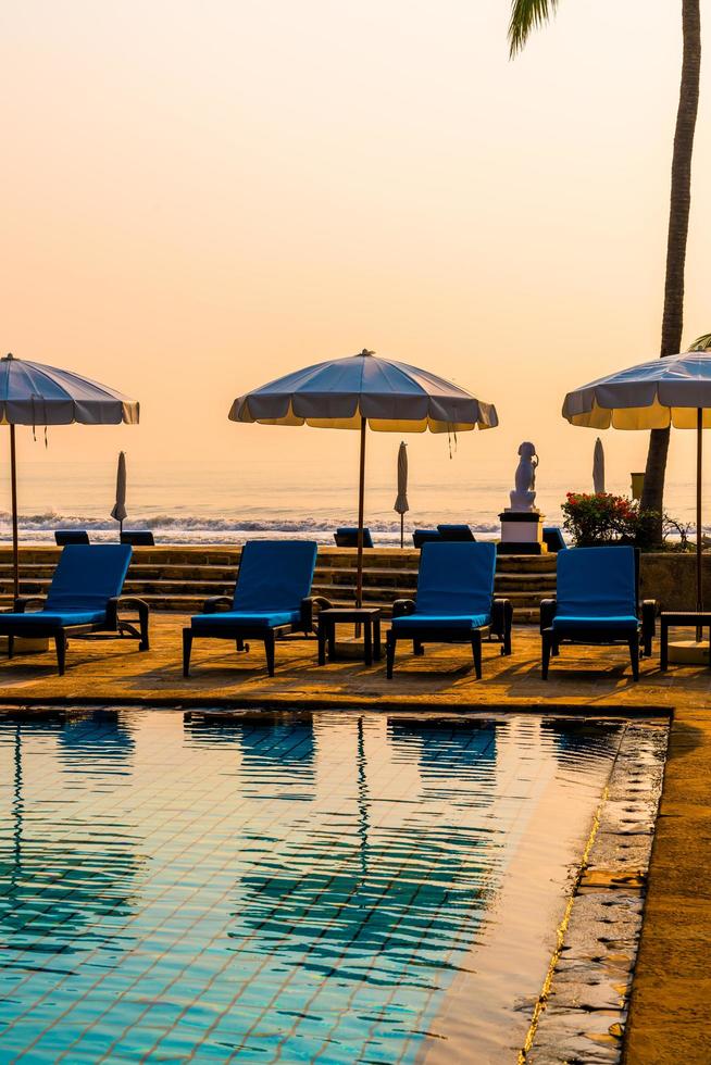 vacker palm med paraplystol pool i lyxhotell semesterort vid soluppgångstider - semester och semester koncept foto