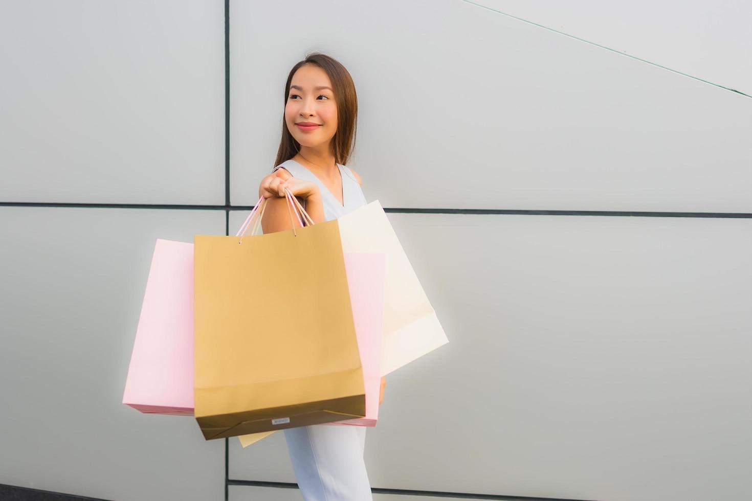 porträtt vacker ung asiatisk kvinna glad och leende med shopping väska från varuhuset foto