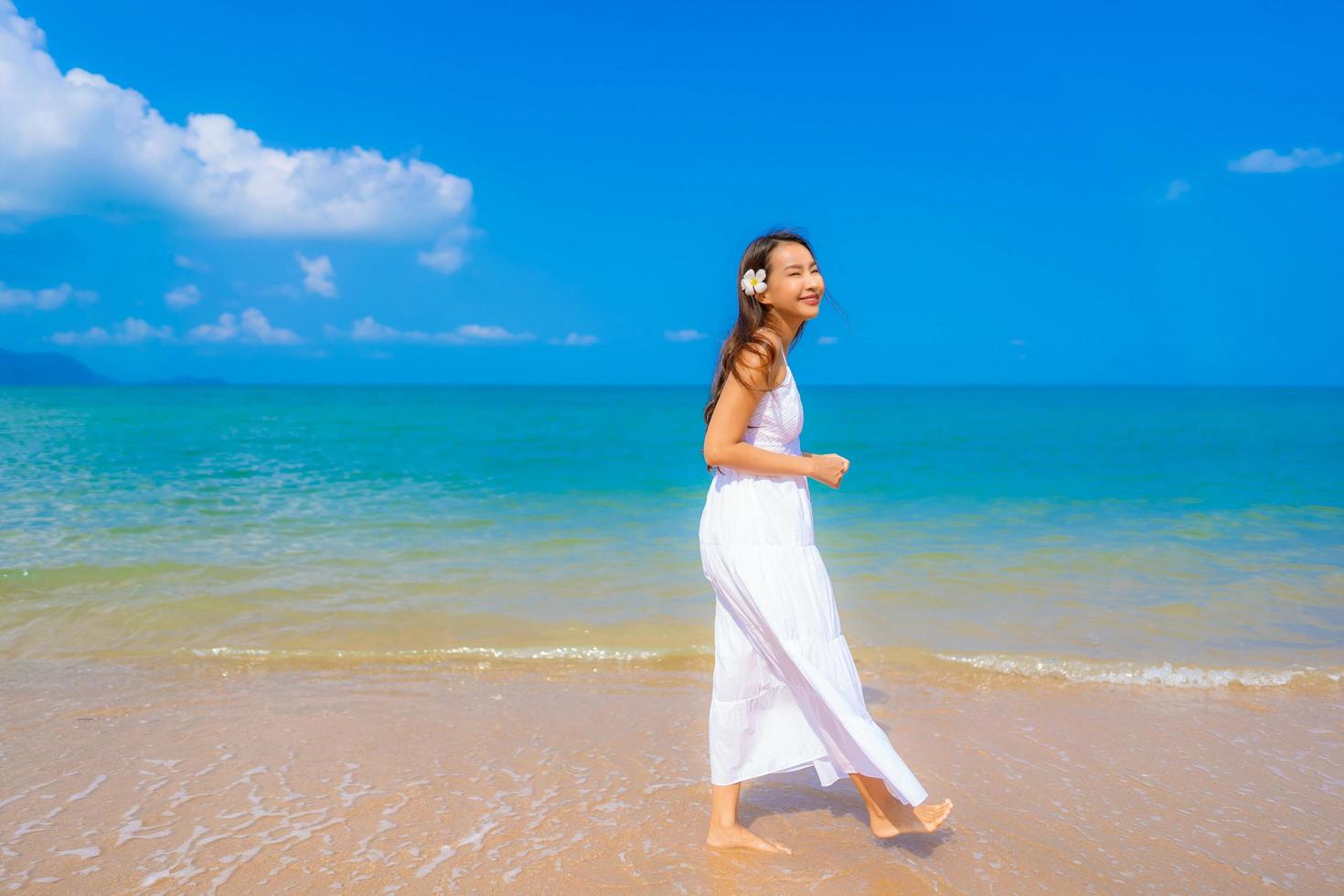 porträtt vacker ung asiatisk kvinna lyckligt leende fritid på stranden havet och havet foto