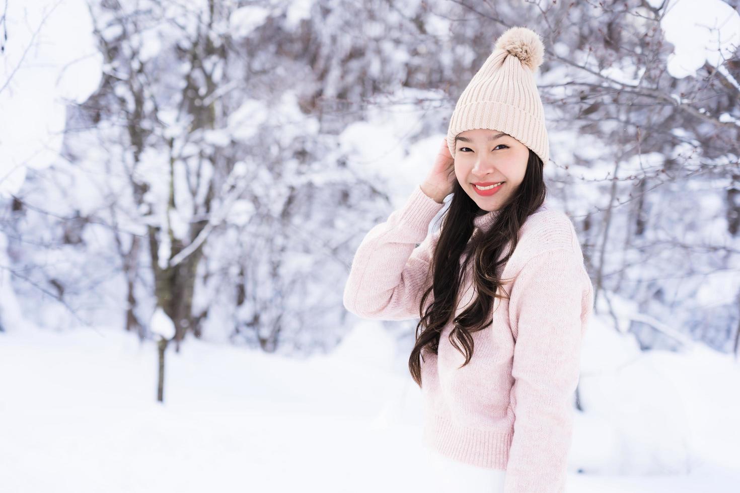 stående ung vacker asiatisk kvinna leende lycklig resa och njut av med snö vintersäsongen foto