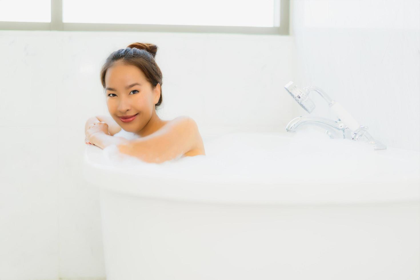 porträtt vacker ung asiatisk kvinna ta ett badkar i badrummet foto