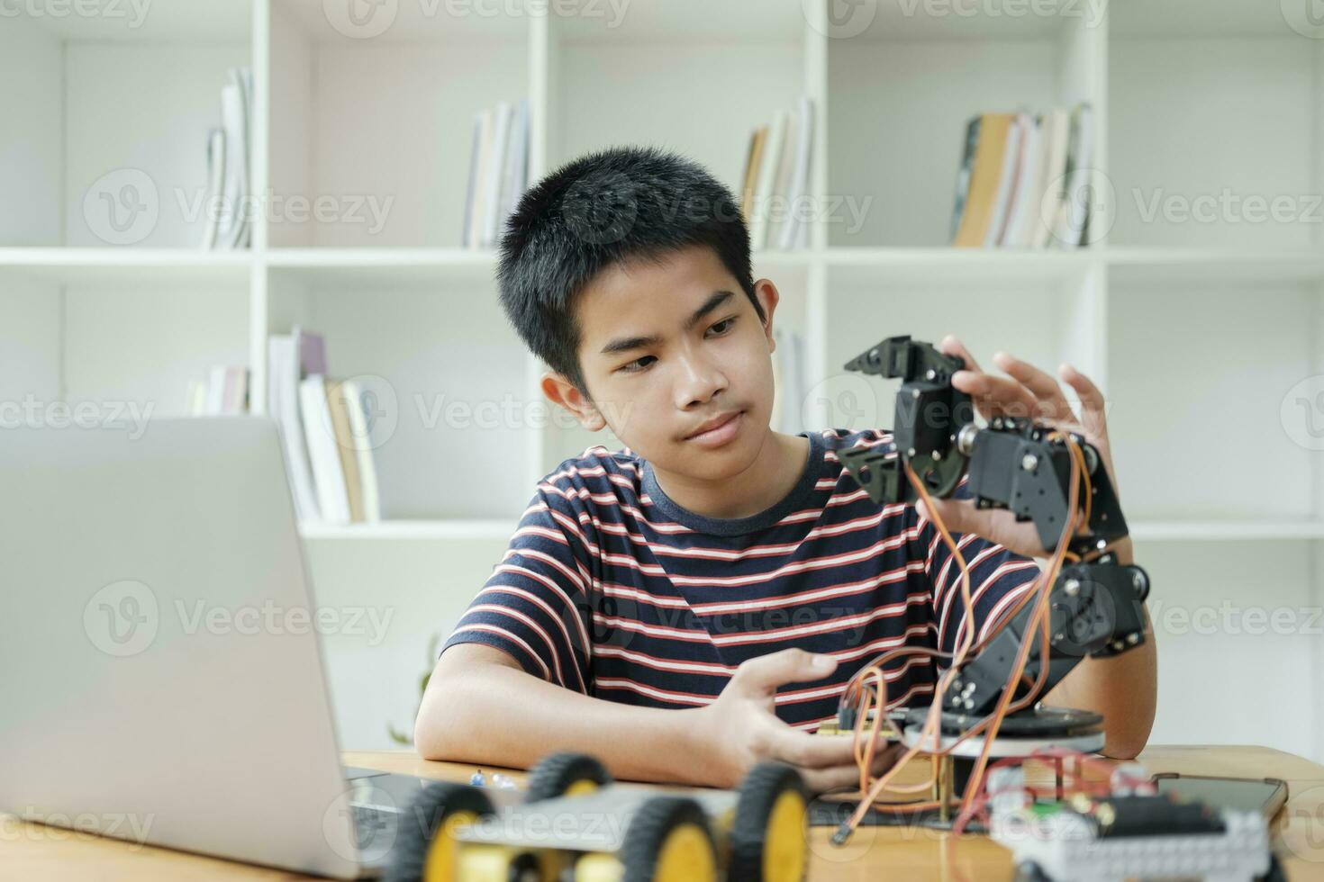 asiatisk tonåring håller på med robot projekt i vetenskap klassrum. teknologi av robotik programmering och stam utbildning begrepp. foto