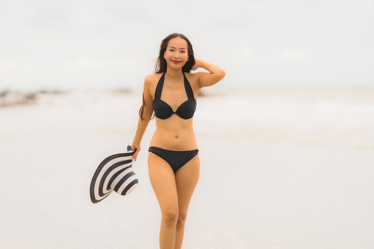 porträtt vacker ung asiatisk kvinna slitage bikini på stranden havet havet foto