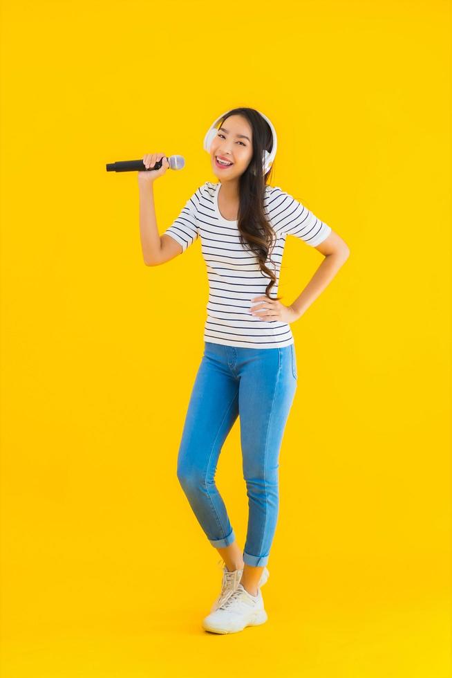 stående vacker ung asiatisk kvinna som sjunger med mikrofon foto
