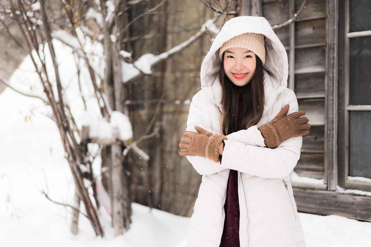 vacker ung asiatisk kvinna som ler glad för att resa i snö vintersäsongen foto