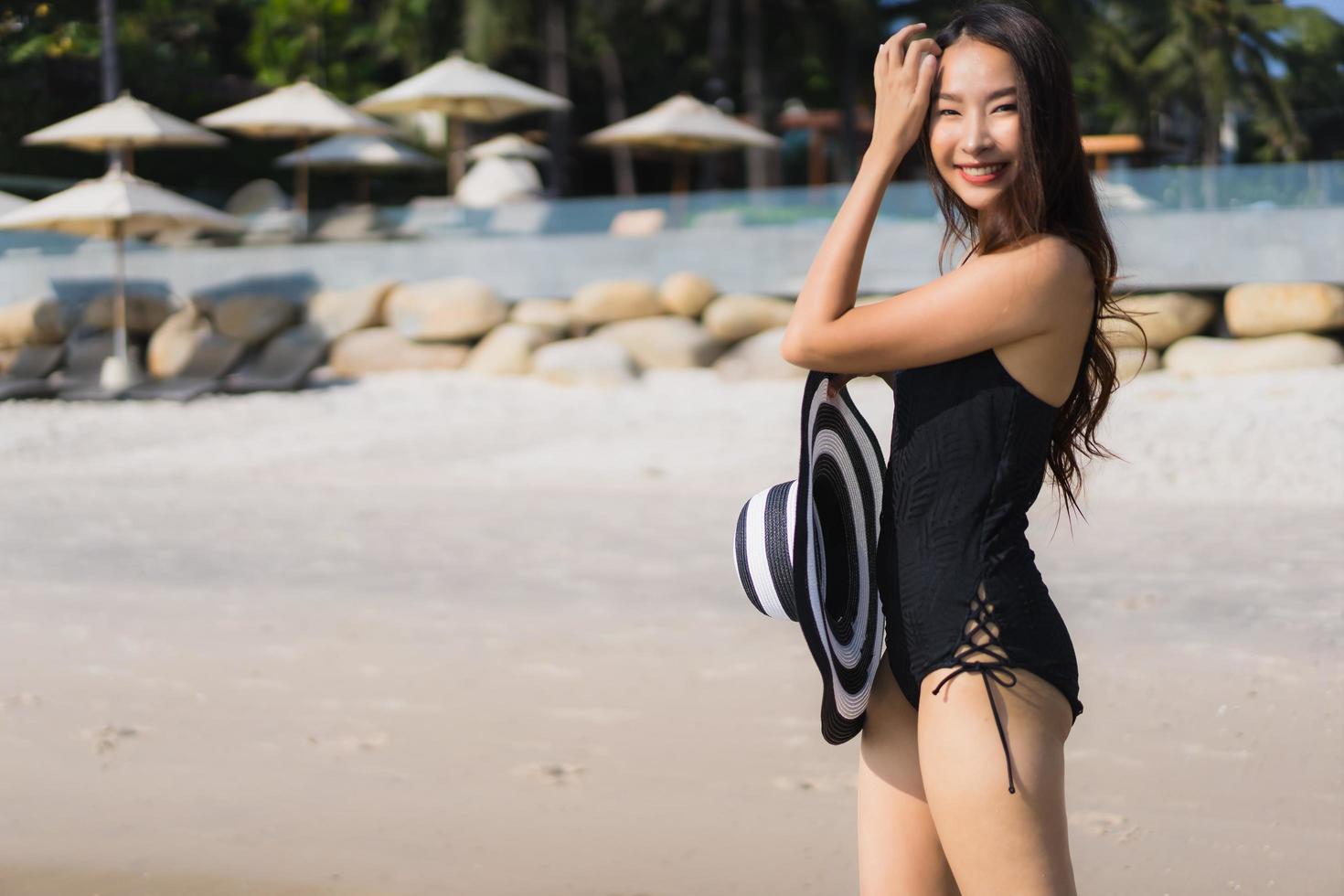 porträtt vacker ung asiatisk kvinna glad och le på stranden och havet foto