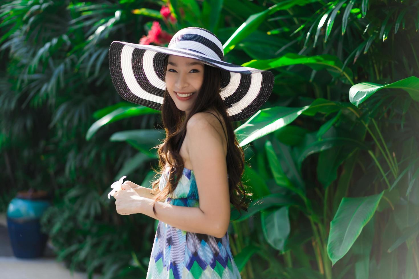porträtt vacker ung asiatisk kvinna leende och glad runt utomhus trädgård foto