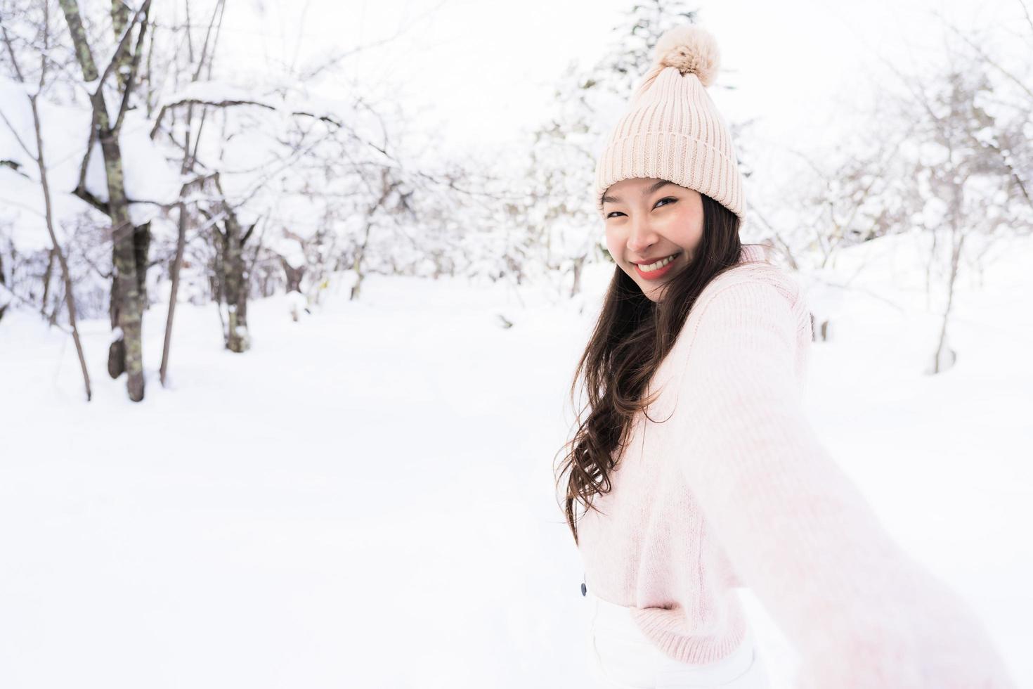 stående ung vacker asiatisk kvinna leende lycklig resa och njut av med snö vintersäsongen foto