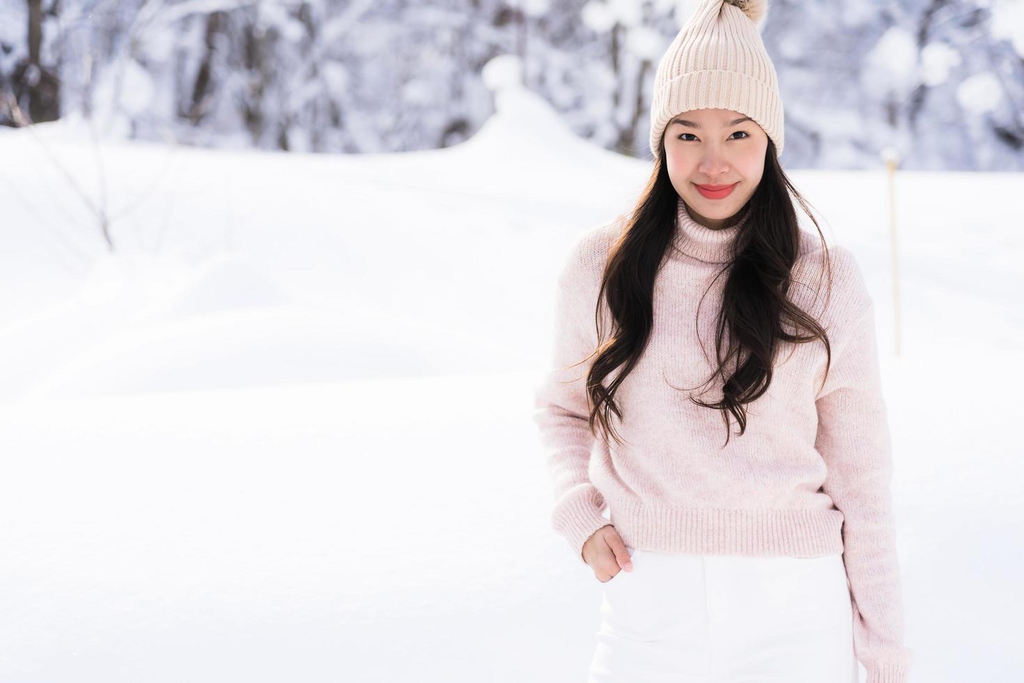 stående ung vacker asiatisk kvinna leende lycklig resa och njut av med snö vintersäsongen foto