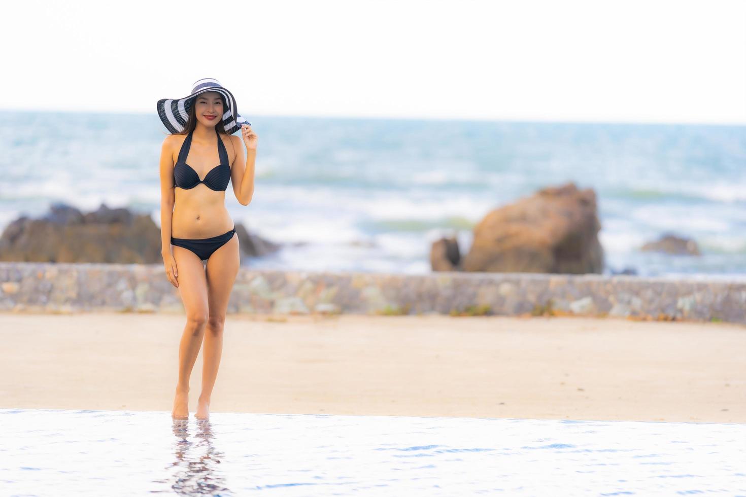 porträtt vacker ung asiatisk kvinna slitage bikini runt poolen i hotellort nästan havet ocean beach foto