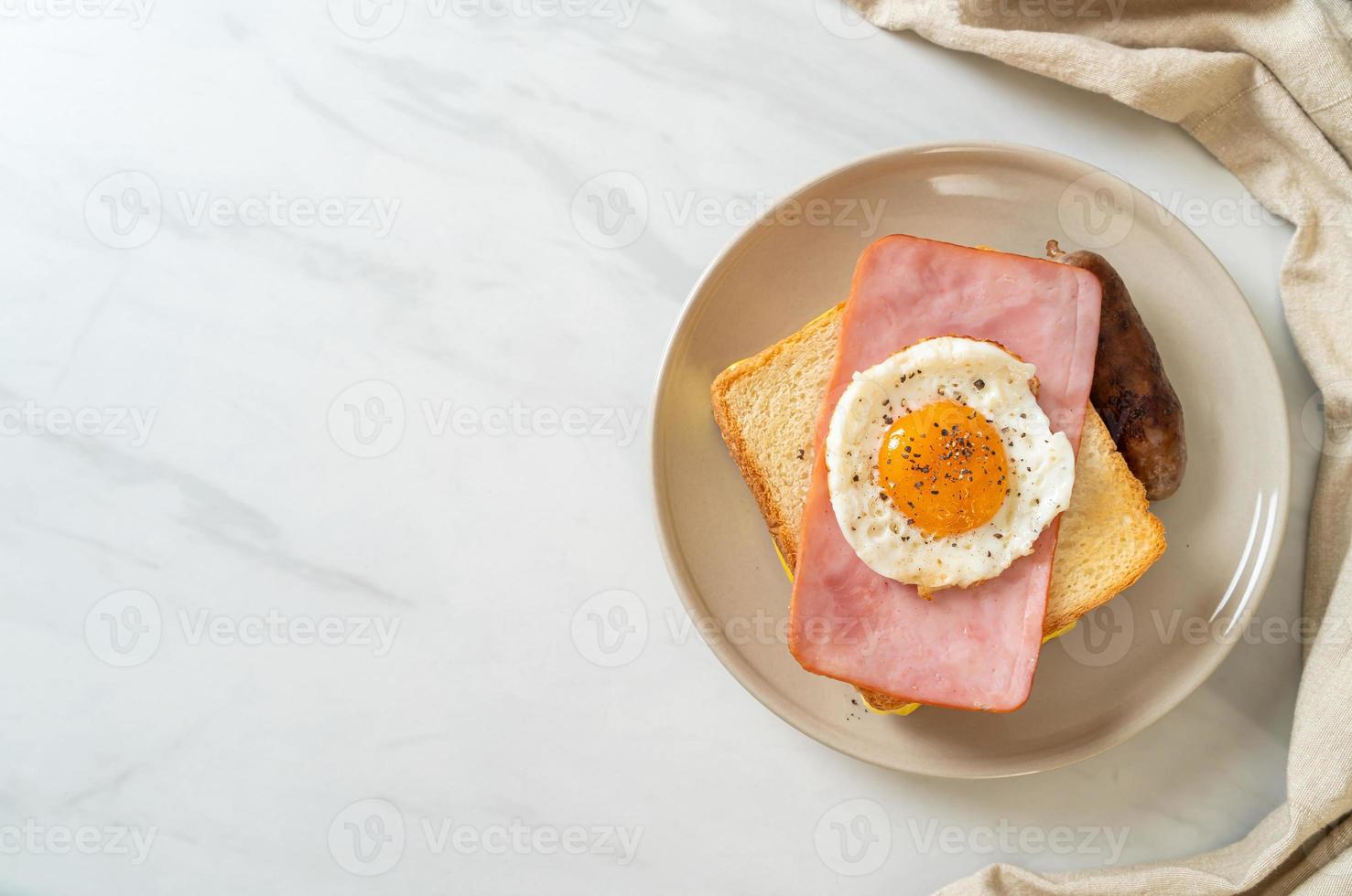 hemlagat bröd rostad ost, toppad skinka och stekt ägg med fläskkorv till frukost foto