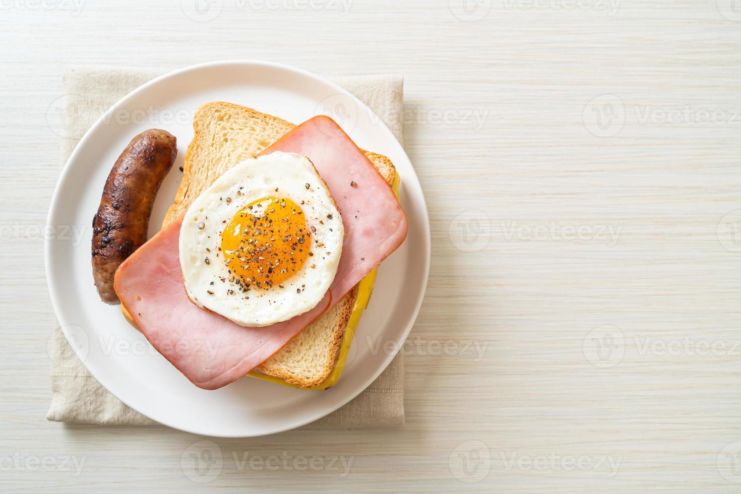 hemlagat bröd rostad ost, toppad skinka och stekt ägg med fläskkorv till frukost foto