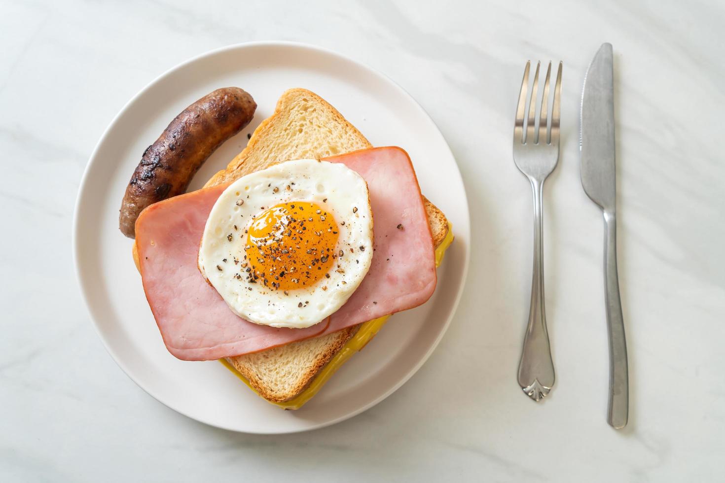 hemlagat bröd rostad ost, toppad skinka och stekt ägg med fläskkorv till frukost foto