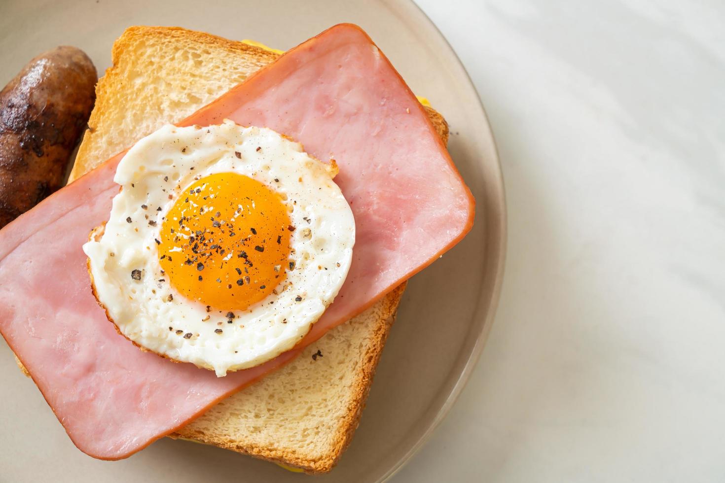 hemlagat bröd rostad ost, toppad skinka och stekt ägg med fläskkorv till frukost foto