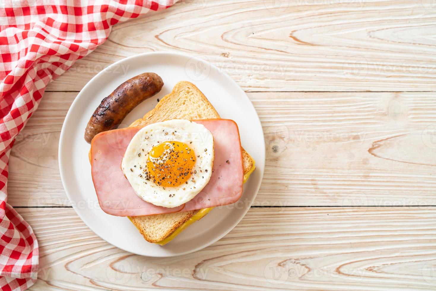 hemlagat bröd rostad ost, toppad skinka och stekt ägg med fläskkorv till frukost foto