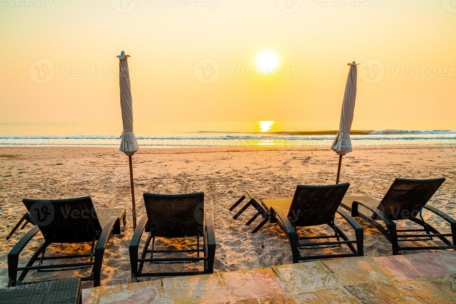 paraplystrandstol med palmträd och havsstrand vid soluppgångstid - semester- och semesterkoncept foto