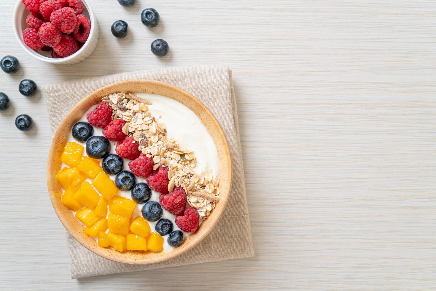 hemlagad yoghurtskål med hallon, blåbär, mango och granola - hälsosam matstil foto