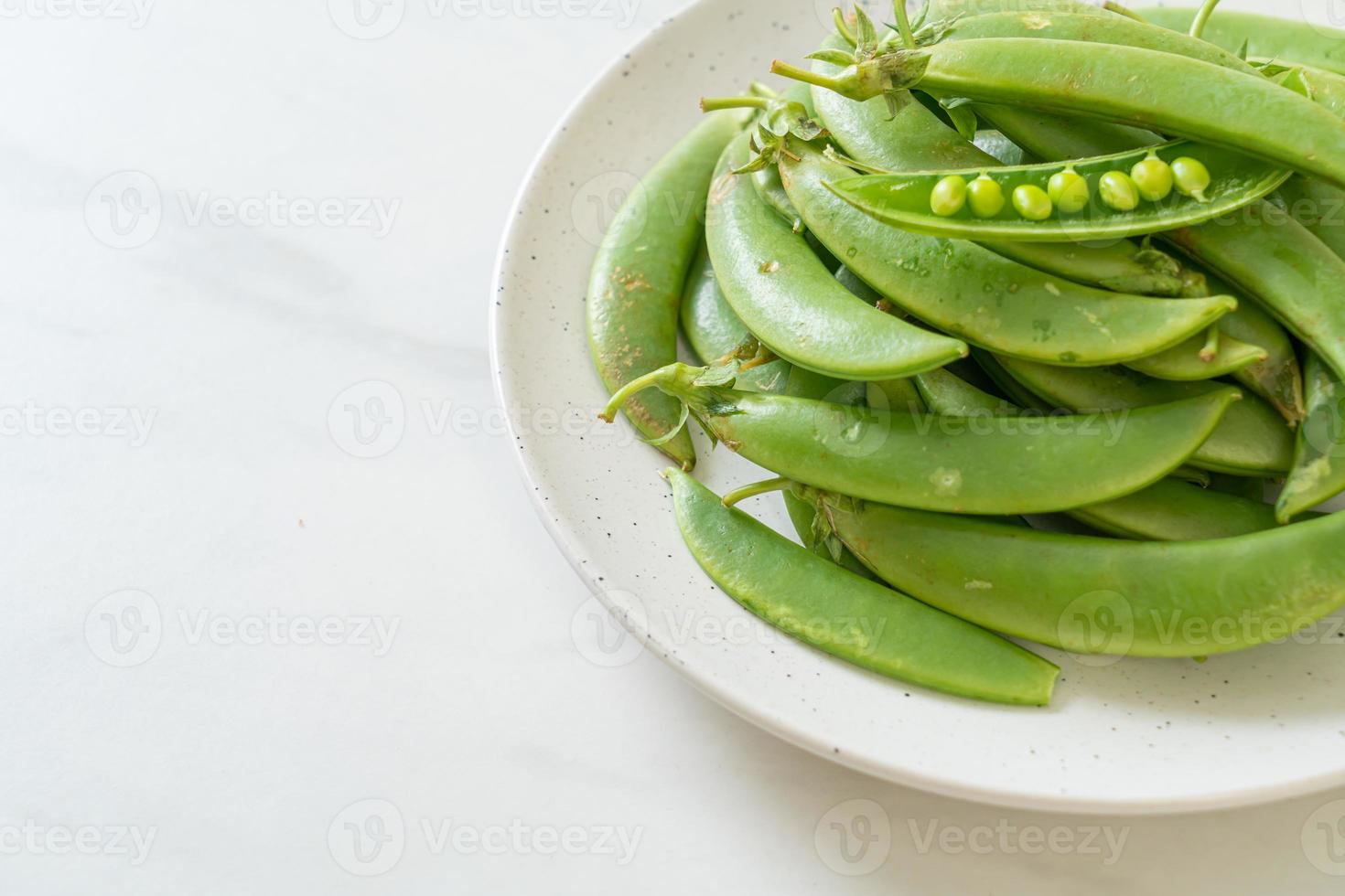 färska söta gröna ärtor på den vita plattan foto