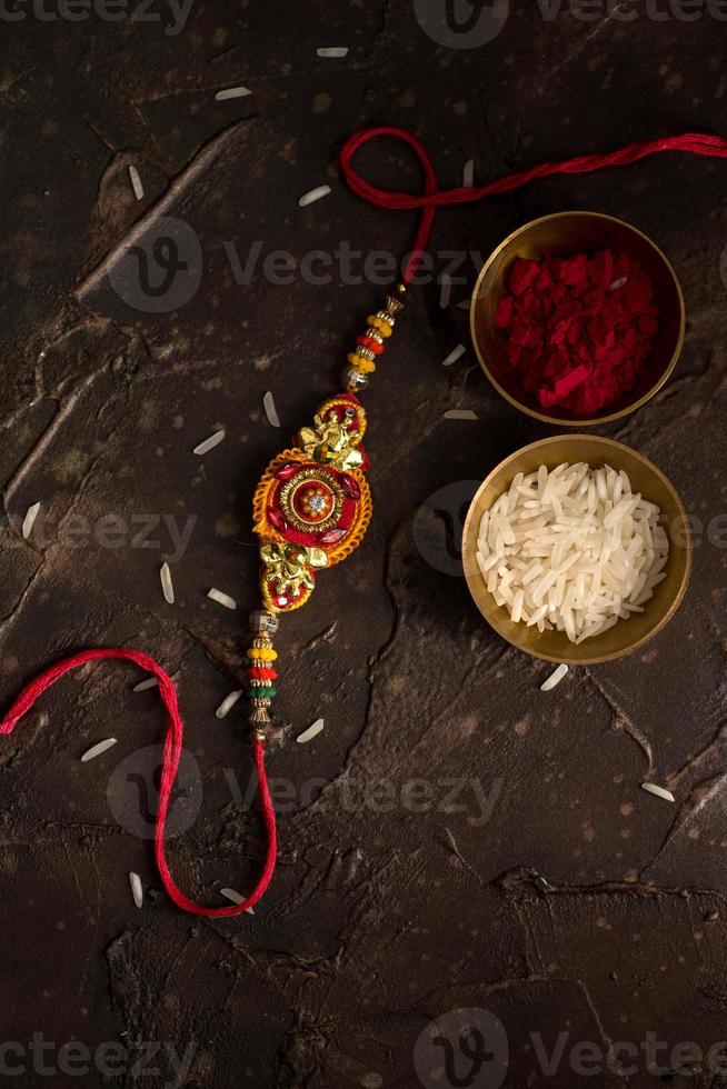 raksha bandhan bakgrund med en elegant rakhi, riskorn och kumkum. ett traditionellt indiskt armband som är en symbol för kärlek mellan bröder och systrar. foto