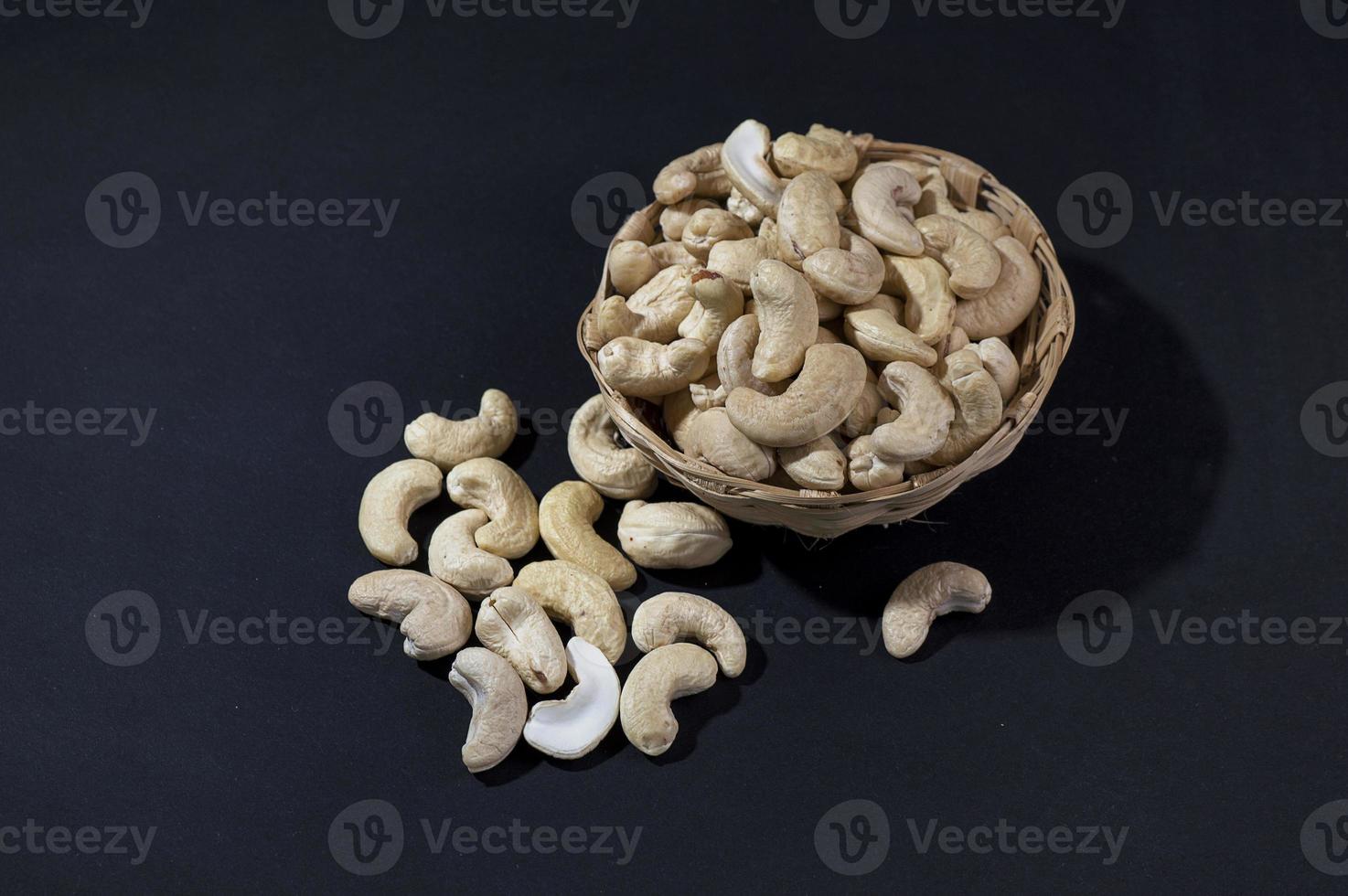 cashewnötter i korg på svart bakgrund foto