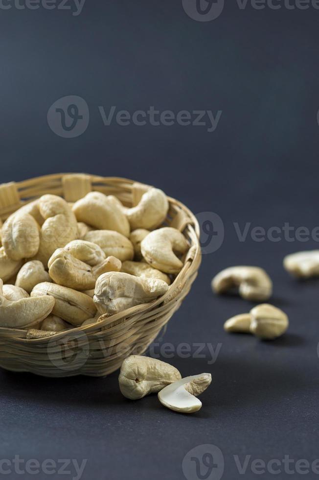 cashewnötter i korg på svart bakgrund foto