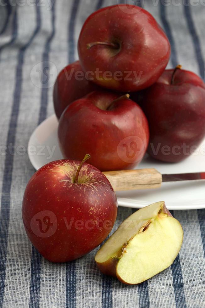 läckra äpplen i tallrik med kniv på randig bordsduk foto